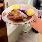 Ein Teller mit Keule, Rotkohl und Klößen wird beim Weihnachtsessen in Dresden ausgegeben
